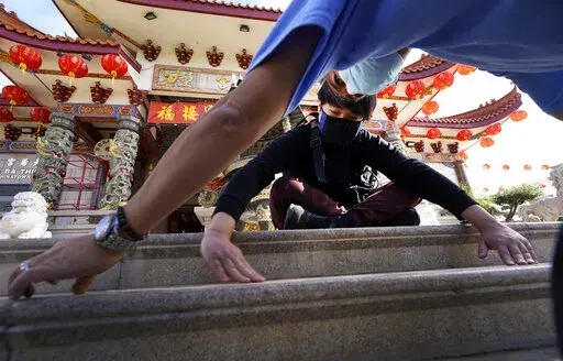 Volunteers, Alex Koi, foreground, and his son Lipsun Koi, 20, help install anti-slip tape on the front steps of the Thien Hau Temple ahead of the crowds expected for the Lunar New Year of the Tiger celebrations in the Chinatown district of Los Angeles, Friday, Jan. 28, 2022. The Lunar New Year of the Tiger celebrations will occur on Feb. 1, amid warnings against travel and large gatherings due to COVID-19. (AP Photo/Damian Dovarganes)