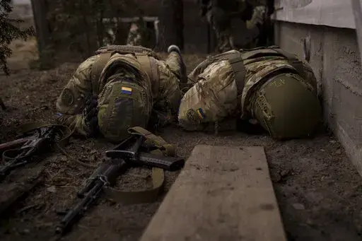 Ukrainian soldiers take cover from incoming artillery fire in Irpin, the outskirts of Kyiv, Ukraine, Sunday, March 13, 2022. (AP Photo/Felipe Dana)