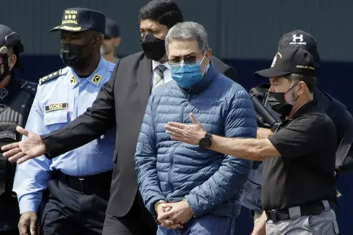 Former Honduran President Juan Orlando Hernandez, second from right, is taken in handcuffs to a waiting aircraft as he is extradited to the United States, at an Air Force base in Tegucigalpa, Honduras, April 21, 2022. Hernandez was sentenced Wednesday, June 26, 2024 in New York, for his conviction on charges that he enabled drug traffickers to use his military and national police force to help get tons of cocaine into the United States. (AP Photo/Elmer Martinez, File)