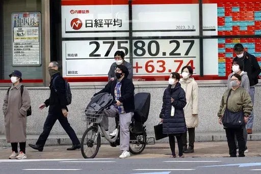 People wait for a traffic light to change in front of an electronic stock board showing Japan's Nikkei 225 index at a securities firm Thursday, March 2, 2023, in Tokyo. Asian stock markets were mixed Thursday after signs of enduring upward pressure on American prices added to expectations of higher interest rates for longer. (AP Photo/Eugene Hoshiko)