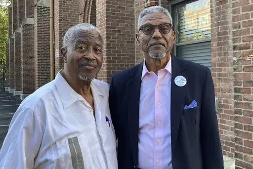 Chester Deanes, left, and Ben Phillips hold a photo of the former Pruitt-Igoe housing development in St. Louis, where they lived growing up on Sept. 7, 2023. The Army sprayed a potential carcinogen from the tops of buildings and from station wagons in the area around Pruitt-Igoe in the 1950s and 1960s as part of secret Cold War-era testing. Deanes and Phillips are leading an effort to get government compensation. (AP Photo/Jim Salter)
