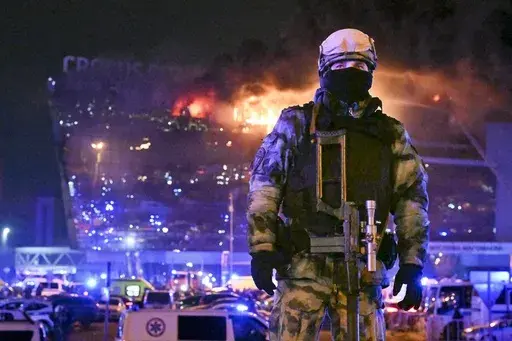 A Russian soldier secures an area as a massive blaze can be seen over a concert venue on the western edge of Moscow, Russia, Friday, March 22, 2024. The attack on a suburban Moscow concert hall that killed over 140 people marked a major failure of Russian security agencies. (AP Photo/Dmitry Serebryakov, File)