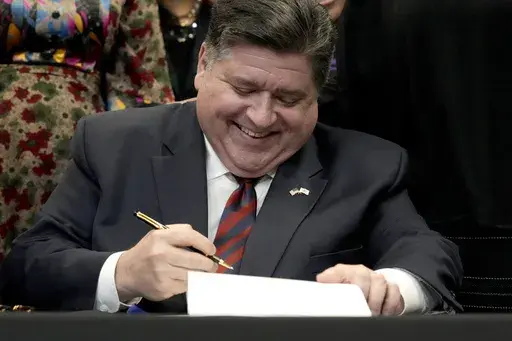 Illinois Gov. J.B. Pritzker signs into law the Paid Leave For All Workers Act on Monday, March 13, 2023, in Chicago. Illinois became one of three U.S. states to require employers to offer paid time off for any reason starting in January of 2024. (AP Photo/Charles Rex Arbogast)