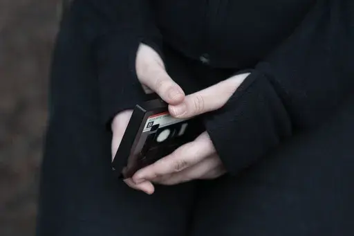 A teenager holds her phone as she sits for a portrait near her home in Illinois, on Friday, March 24, 2023. The U.S. Surgeon General is warning there is not enough evidence to show that social media is safe for young people — and is calling on tech companies, parents and caregivers to take "immediate action to protect kids now." (AP Photo Erin Hooley, File)