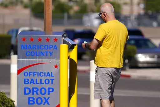 A voter places a ballot in an election voting drop box in Mesa, Ariz., Friday, Oct. 28, 2022. (AP Photo/Ross D. Franklin)