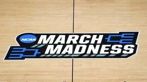 FILE -The March Madness logo is shown on the court during the first half of a men's college basketball game in the first round of the NCAA tournament at Bankers Life Fieldhouse in Indianapolis, Saturday, March 20, 2021. Kansas, Villanova, North Carolina and Duke will play in the first Final Four to take place under the new world of “name, image and likeness” endorsements in college sports. It allows college players to earn money through endorsements. (AP Photo/Paul Sancya, File)