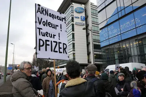 A demonstrator holds a placard reading "Scammer, thief, killer, Pfizer" during a protest against the vaccine pass and vaccinations to protect against COVID-19 in front of the Pfizer headquarters, in Paris, on Jan. 29, 2022. An anti-vaccine group that has harassed doctors and public officials in Italy and France is still active on platforms like Facebook despite efforts to rein in their abuse and misinformation. The organization, known as V_V, bombards its victims with dozens, hundreds or even th