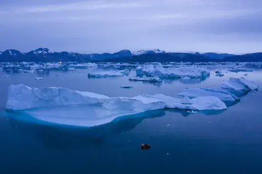 A boat navigates at night next to large icebergs near the town of Kulusuk, in eastern Greenland on Aug. 15, 2019. A new massive study finds that Greenland and Antarctic ice sheets are now losing more than three times as much ice a year as they were 30 years ago. (AP Photo/Felipe Dana, File)