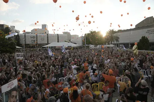 Family, friends and supporters of Ariel Bibas, who is held hostage by Hamas in the Gaza Strip, release orange balloons to mark his fifth birthday in Tel Aviv, Israel, Monday, Aug. 5, 2024. Ariel Bibas, who along with his 1-year-old brother Kfir, has become a symbol of the struggle to free the hostages who remain captive in Gaza. The orange balloons are meant to symbolize Ariel and Kfir's bright red hair. (AP Photo/Mahmoud Illean)