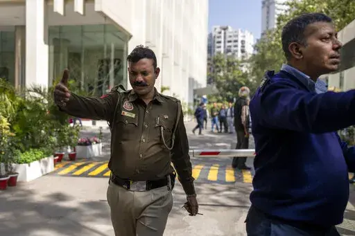 A police officer and a private security guard ask journalists to leave from the gate of a building housing BBC office in New Delhi, India, Tuesday, Feb. 14, 2023. Officials from India's Income Tax department began conducting searches Tuesday at the BBC's offices in the capital, New Delhi, three of the broadcaster's staff members told the Associated Press. (AP Photo/Altaf Qadri)
