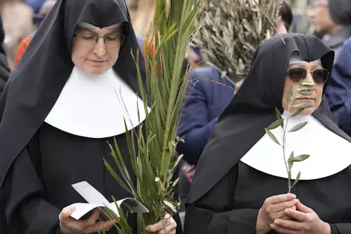 Nuns wait for the start of the Palm Sunday's mass celebrate by pope Francis in St. Peter's Square at The Vatican Sunday, April 2, 2023. Palm Sunday will be celebrated by Christians worldwide Sunday, March 24, 2024. It commemorates the Christian belief in the triumphant entry of Jesus into Jerusalem, when palm branches were strewn before him. It marks the start of Holy Week. (AP Photo/Andrew Medichini)