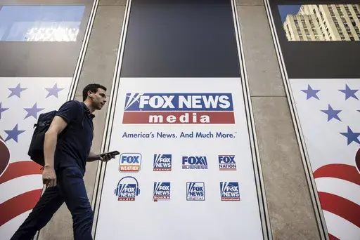 A person walks past the Fox News Headquarters in New York on April 12, 2023. Fox News will pay one of its former producers $12 million to settle her claims that she faced a discriminatory workplace and that the network tried to coerce her into giving false testimony in Dominion Inc.’s defamation lawsuit against the network, her lawyer said Friday, June 30, 2023. (AP Photo/Yuki Iwamura, File)