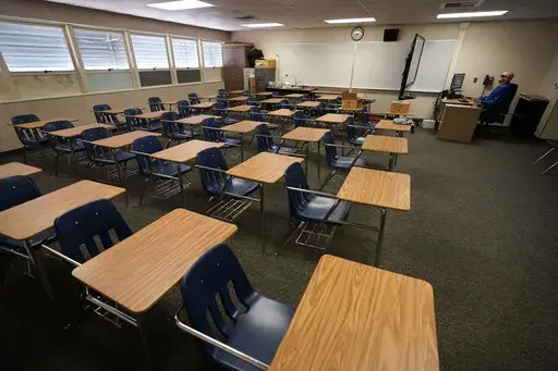 Math teacher Doug Walters sits among empty desks as he takes part in a video conference with other teachers to prepare for at-home learning at Twentynine Palms Junior High School in Twentynine Palms, Calif., Aug. 18, 2020. A new study finds that students around the world suffered historic setbacks in reading during the pandemic and even deeper losses in math, with test score decreases so wide that the United States climbed in global rankings simply by falling behind less sharply. (AP Photo/Grego