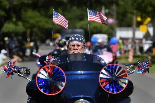 Flags and patriotic stars flutter and twirl as Dwane Tervooren rides with other motorcyclists during Tuesday's Independence Dayparade in Buffalo Gap, Texas Tuesday, July 4, 2023. (Ronald W. Erdrich /The Abilene Reporter-News via AP)