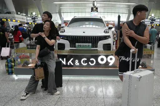 Passengers wait near a hybrid luxury SUV from China automaker Lynk&co displayed at the train station in Hangzhou in eastern China's Zhejiang province on Monday, July 3, 2023. Chinese automakers are winning over drivers as they make major inroads into Europe’s electric vehicle market, challenging long-established homegrown brands in an industry that’s key to the continent’s green energy transition. The European Union has launched an investigation into Beijing’s support for its EV industry