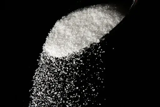 Granulated sugar is poured using a spoon, Sept. 12, 2016, in Philadelphia. New York City residents may soon see warning labels next to sugary foods and drinks in chain restaurants and coffee shops, under a law set to go into effect later in 2024. (AP Photo/Matt Rourke, File)