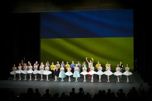 Ukrainian dancers of the Kyiv City Ballet company acknowledge applause in front of Ukrainian flag projected onto a screen at the end of a performance, at the Theatre de Chatelet, in Paris, Tuesday, March 8, 2022. The Kyiv City Ballet danced to a full house in Paris for the last show of a French tour that has left the company stranded after the war broke out in Ukraine. They described being physically and emotionally exhausted. Being given the opportunity to train and dance was for many a chance 