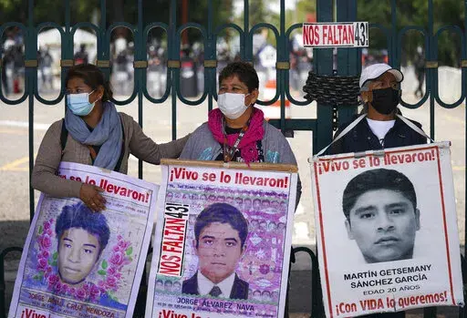 Relatives of the missing 43 Ayotzinapa students hold signs that read in Spanish "You took them alive, We want them back alive" during a protest outside a military base in Mexico City, Friday, Sept. 23, 2022, days before the anniversary of the disappearance of the students in Iguala, Guerrero in 2014. One week prior, Mexican authorities said they arrested a retired general and three other members of the army for alleged connection to their disappearance. (AP Photo/Fernando Llano)