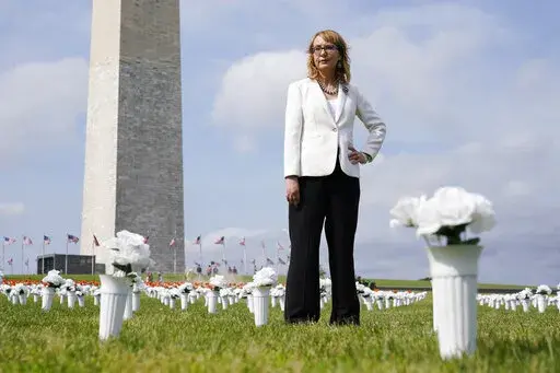 Former congresswoman and gun violence survivor Gabby Giffords stands among vases of flowers that make up the Gun Violence Memorial installation near the Washington Monument on the National Mall in Washington, Tuesday, June 7, 2022. The flowers are meant to represent the number of Americans who die from gun violence each year. (AP Photo/Patrick Semansky)