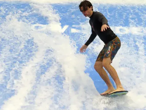 A man rides a surfboard on a surfing simulator during a preview of the Island Waterpark in Atlantic City, N.J., Thursday, June 22, 2023. The $100 million park, which will open June 30, is part of an effort by Atlantic City to offer guests — particularly those with children — something to do other than gambling. It's a strategy Las Vegas has been using to great effect. (AP Photo/Wayne Parry)