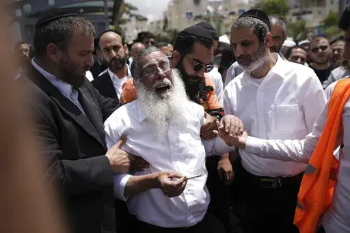 Ultra-Orthodox Jewish mourners encircle a man overcome with grief at the funeral for Yonatan Havakuk and Boaz Gol, a day after they were killed in a stabbing attack in Elad, Israel, Friday, May 6, 2022. Israeli security forces waged a massive manhunt Friday for two Palestinians suspected of carrying out the stabbing attack on Thursday near Tel Aviv that left three Israelis dead. (AP Photo/Ariel Schalit)