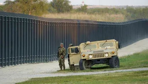 National Guardsmen stands watch over a fence near the International bridge where thousands of Haitian migrants have created a makeshift camp, on Sept. 18, 2021, in Del Rio, Texas. Former Trump administration officials are pressing Republican border governors to declare an "invasion" along the U.S.-Mexico border. It comes as Texas Gov. Greg Abbott says he'll announce "unprecedented actions" on Wednesday to deter migrants coming to Texas. (AP Photo/Eric Gay, File)