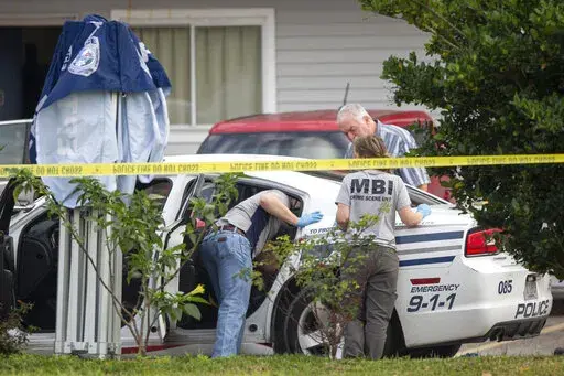 Mississippi Bureau of of Investigations investigators inspected a police vehicle on the scene of the murder of two police officers outside a Motel 6 in Bay St. Louis, Miss. on Tuesday, Dec. 13, 2022. Police say a woman shot and killed two officers before killing herself. (Hannah Ruhoff/The Sun Herald via AP)