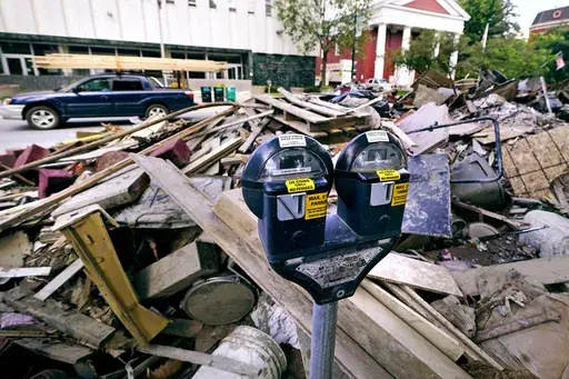 Flooding debris is stacked along State Street, near the state capital building, as a vehicle drives past with a load of lumber tied to the roof in downtown, Tuesday, Aug. 1, 2023, in Montpelier, Vt. The mostly gutted shops, restaurants and businesses that lend downtown Montpelier its charm are considering where and how to rebuild in an era when extreme weather is occurring more often. Vermont's flooding was just one of several major flood events around the globe this summer that scientists have 
