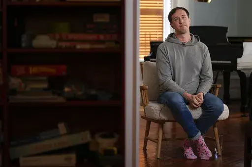 Samuel Schultz talks to reporters at his home, Monday, Oct. 9, 2023, in New York. It took eight years and the burgeoning #MeToo movement to spur them to go public and make a police report, and an additional five years for their attackers to plead guilty. Now, as much as Schultz hopes there’s a reckoning coming in gay and queer communities, too, it feels like they are the ones shouldering the blame, not the attackers: for coming forward, for harming the men’s reputations. (AP Photo/Seth Wenig