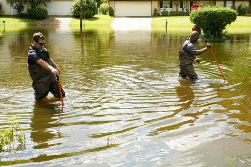 Hinds County Emergency Management Operations deputy director Tracy Funches, right, and operations coordinator Luke Chennault, wade through flood waters in northeast Jackson, Miss., on Aug. 29, 2022, as they check water levels. A federal agency has set aside money to help guard Mississippi’s capital city and surrounding areas against flood damage following two deluges in three years. The U.S. Army Corps of Engineers announced Monday, Oct. 3, 2022, that it has budgeted $221 million to help fund 