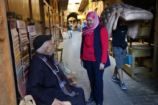 Hania Zaatari, center, who is an independent candidate in the upcoming parliamentary elections tells a man that fixing Lebanon's devastating economic crisis is her top priority, at the old souk, in  Sidon, Lebanon, April 9, 2022. The May 15 nationwide vote is the first since Lebanon's economy took a nosedive and an August 2020 explosion at Beirut's port killed more than 200 and destroyed parts of the capital. Lebanon's various disasters have fueled anger at Lebanon's political elite, but few see