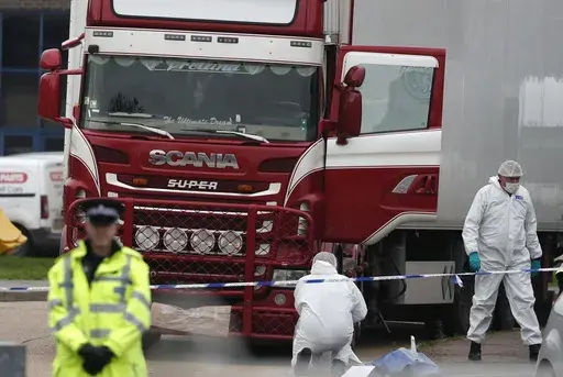 Forensic police officers attend the scene after a truck was found to contain a large number of dead bodies, in Grays, England, Oct. 23, 2019. A Romanian man who was part of an international human smuggling ring was sentenced Tuesday July 11, 2023, to more than 12 years in prison for the deaths of 39 migrants from Vietnam who suffocated were found lifeless in a truck trailer in England in 2019. Marius Mihai Draghici, 50, pleaded guilty last month to 39 counts of manslaughter and conspiracy to ass