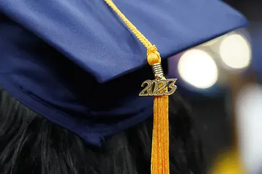 A tassel with 2023 on it rests on a graduation cap as students walk in a procession for Howard University's commencement in Washington, May 13, 2023. Deciding how to spend your first paycheck after graduating from college can be overwhelming, given the many competing demands on it. In addition to necessities like rent, food and transportation, new grads often also have student loans and credit card debt to pay down. Financial experts suggest first choosing the budgeting style that works best for