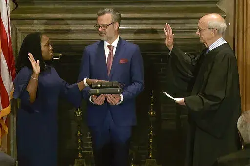 In this image from video provided by the Supreme Court, retired Supreme Court Associate Justice Stephen Breyer administers the Judicial Oath to Ketanji Brown Jackson as her husband Patrick Jackson holds the Bible at the Supreme Court in Washington, Thursday, June 30, 2022. (Supreme Court via AP)