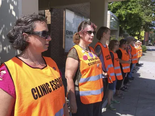 Escort volunteers line up outside the EMW Women's Surgical Center, on Monday, July 17, 2017, in Louisville, Ky. A pregnant woman in Kentucky who filed a lawsuit demanding the right to an abortion has learned her embryo no longer has cardiac activity, her attorneys said Tuesday, Dec. 12, 2023. Her attorneys didn't immediately comment on what effect the development would have on the lawsuit filed last week in a state court in Louisville. (AP Photo/Dylan Lovan, File)