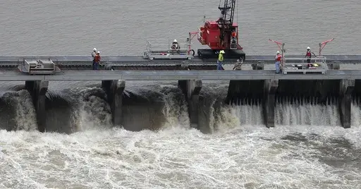 Workers open bays of the Bonnet Carre Spillway to divert rising water from the Mississippi River to Lake Pontchartrain, upriver from New Orleans, in Norco, La., May 10, 2019. Several local governments and business groups on the Mississippi Gulf Coast filed a lawsuit Monday, Jan. 22, 2024, saying that the U.S. Army Corps of Engineers' opening of the spillway in 2019 sent polluted fresh water from the Mississippi River into the Gulf of Mexico and killed bottlenose dolphins that live in saltwater. 