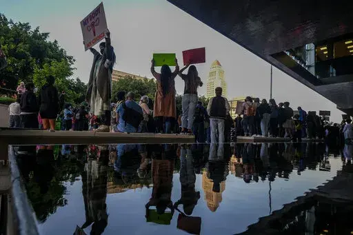 Demonstrators are reflected in a pond as they protest outside of the U.S. Courthouse in response to a leaked draft of the Supreme Court's opinion to overturn Roe v. Wade, in Los Angeles, March 3, 2022. (AP Photo/Ringo H.W. Chiu, File)