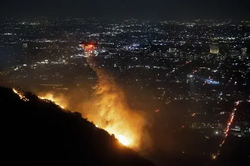 Water is dropped by helicopter on the burning Sunset Fire in the Hollywood Hills section of Los Angeles, Wednesday, Jan. 8, 2025. (AP Photo/Ethan Swope)