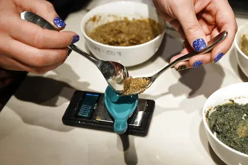 Rabbi Ben Gorelick, measures out a precise amount Sacrament, psilocybin mushrooms, during Sacred Tribe Sacrament ceremony at the Synagogue, his home, on Nov. 6, 2021, in Denver. Colorado voters are deciding whether theirs will be the second state, after Oregon, to decriminalize psychedelic mushrooms for those 21 and older. A ballot measure would create state-regulated "healing centers" for patients to experience the drug. (Andy Cross/The Denver Post via AP, File)