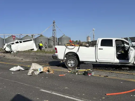 In this photo provided by KIFI Local News 8, a pickup truck crashed into a passenger van on U.S. Highway 20, Saturday, May 18, 2024, in Idaho Falls, Idaho. State police say the accident happened early Saturday morning when a pickup crossed the centerline on U.S. Highway 20 and fatally hit a passenger van. (Jeff Roper/KIFI Local News 8 via AP)