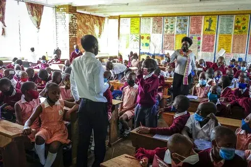 Pupils wear face masks as they attend class at Kitante Primary School in Kampala, Uganda Monday, Jan. 10, 2022. Uganda's schools reopened to students on Monday, ending the world's longest school disruption due to the COVID-19 pandemic. (AP Photo/Hajarah Nalwadda)