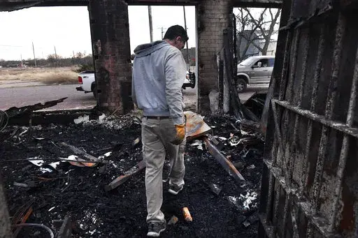 Jared Calvert exits the former Ranger Law Enforcement Center in Ranger, Texas Friday March 18, 2022.  Fire crews in West Texas hope to make progress Saturday against a massive complex of wildfires that have killed one person and burned at least 50 homes, officials said. (Ronald W. Erdrich/The Abilene Reporter-News via AP)