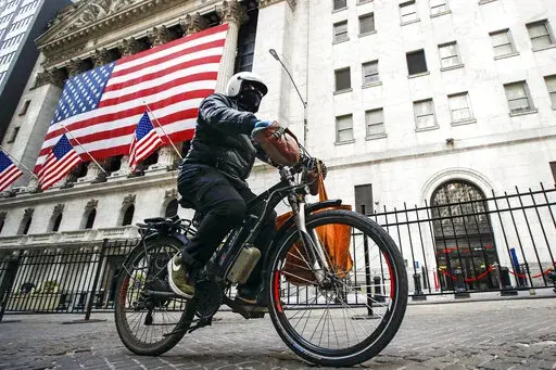 A delivery worker rides his electric bicycle past the New York Stock Exchange, March 16, 2020, in New York.Lithium ion batteries used to power electric bicycles and scooters have already sparked 22 fires that caused 36 injuries and two deaths in New York City this year, four times the number of fires linked to the batteries by this time last year, city officials said Friday, Feb. 24, 2023. (AP Photo/John Minchillo, File)