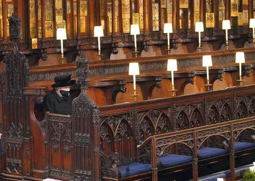 Britain's Queen Elizabeth II sits alone in St. George's Chapel during the funeral of Prince Philip, the man who had been by her side for 73 years, at Windsor Castle, Windsor, England, Saturday April 17, 2021. Boris Johnson's former communications chief has apologized "unreservedly" on Friday for a lockdown-breaching party in Downing Street last year. The Daily Telegraph said Downing Street staff drank, danced and socialized on April 16 last year, the night before the funeral of Prince Philip. Th