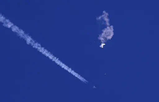 A fighter jet flies past the remnants of a large balloon after it was shot down above the Atlantic Ocean, just off the coast of South Carolina near Myrtle Beach, Feb. 4, 2023. The Defense Department and the Federal Aviation Administration have been tracking a balloon that was flying off the coast of Hawaii last week. A defense official says there’s no indication it is connected to China or any other adversary, and it presents no threats to aviation or national security. (Chad Fish via AP, File