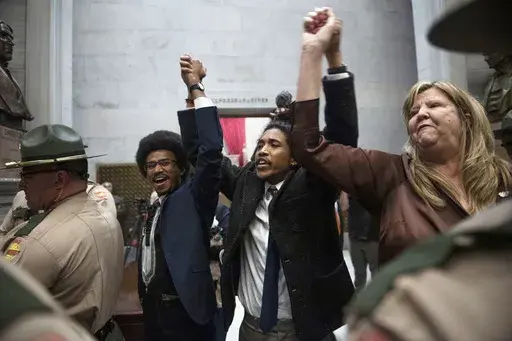 From left, Tennessee state Rep. Justin Pearson, state Rep. Justin Jones and state Rep. Gloria Johnson hold their hands up as they exit the House Chamber doors at Tennessee state Capitol Building in Nashville, Tenn., Monday, April 3, 2023. In Tennessee, three Democratic House members are facing expulsion for using a bullhorn in the House chamber to show support for pro-gun control protesters. In an increasingly polarized political atmosphere, experts say these kinds of harsh punishments for minor