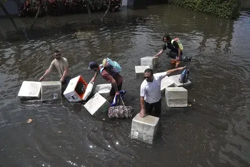 People try and save valuables as they wade through flood waters in the Edgewood neighborhood of Fort Lauderdale, Fla., April 13, 2023. Over 25 inches of rain fell in South Florida since Monday, causing widespread flooding. (Joe Cavaretta/South Florida Sun-Sentinel via AP)