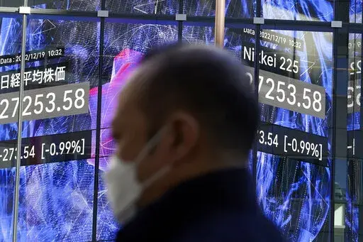 A person stands near an electronic stock board showing Japan's Nikkei 225 index at a securities firm Monday, Dec. 19, 2022, in Tokyo. Asian stock markets fell again Monday as investors wrestled with fears the Federal Reserve and European central banks might be willing to cause a recession to crush inflation. (AP Photo/Eugene Hoshiko)