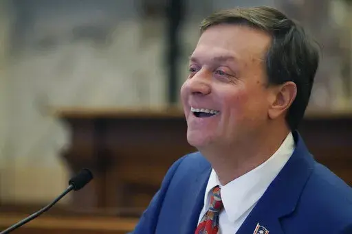Senate Insurance Committee Chairman Walter Michel, R-Ridgeland, breaks into a smile as he attempts to keep a straight face while answering questions about legislation on establishing provisions for the sale and renewal of pet insurance policies, in the Senate Chamber at the Mississippi Capitol in Jackson, Wednesday, Feb. 1, 2023. As the bill's presenter, Michel took some good natured ribbing from members. (AP Photo/Rogelio V. Solis)