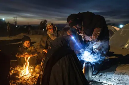 A family prepares tea outside the Directorate of Disaster office where they are camped, in Herat, Afghanistan, on Nov. 29, 2021. As winter deepens, a grim situation in Afghanistan is getting worse. Freezing temperatures are compounding the misery from the downward spiral that has come with the fall of the U.S.-backed government and the Taliban takeover. Aid groups and international agencies estimate about 23 million people, half the country, face severe hunger and nearly 9 million are on the bri